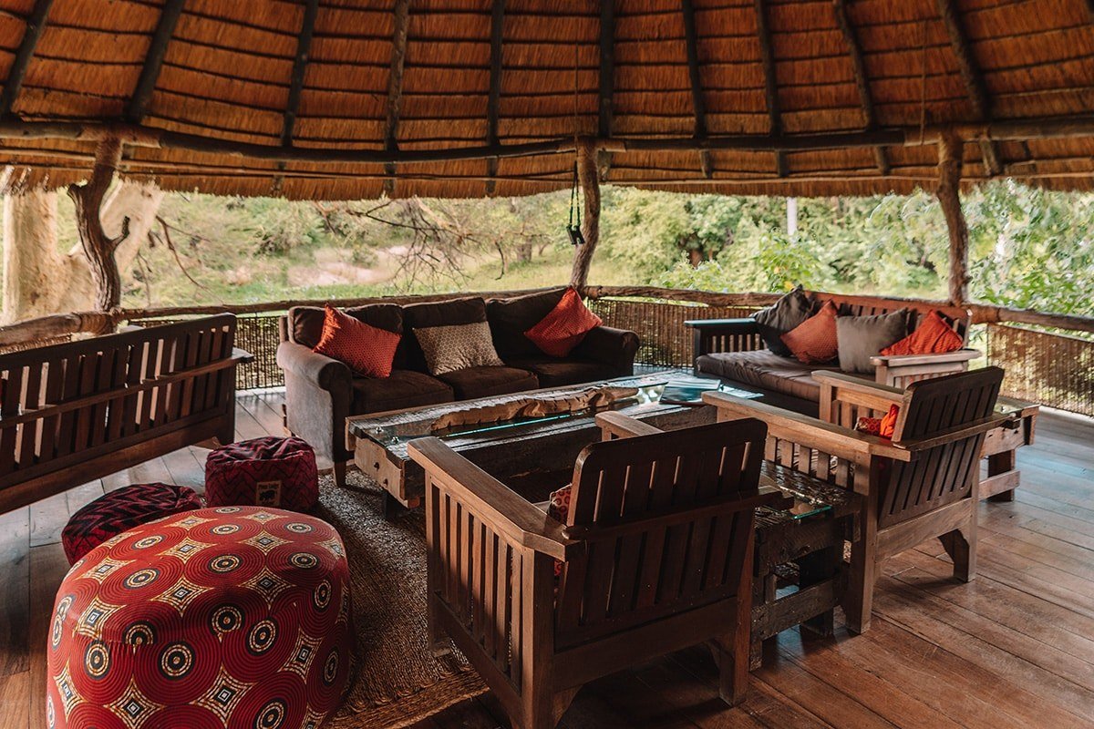 Strohgedeckte Lounge mit Sitzkissen und Blick auf die Buschlandschaft in Mvuu Lodge